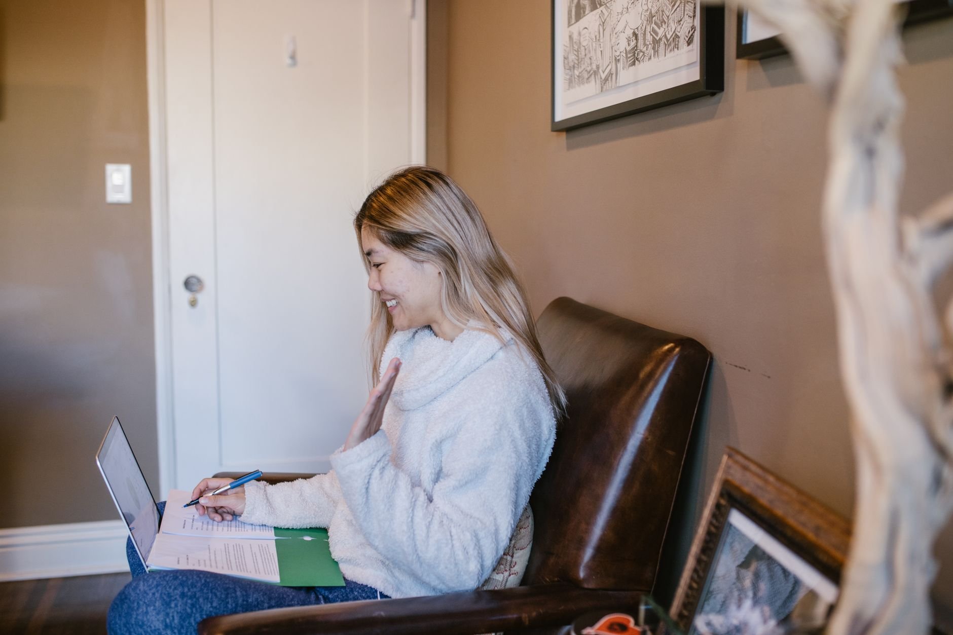 Woman smiling and waving during a live online class from home